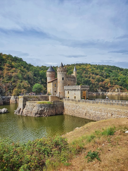 gray concrete castle near river under cloudy sky during daytime in Loire France