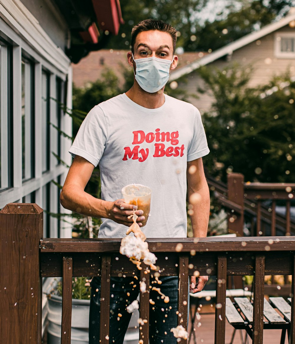 man in white crew neck t-shirt holding brown dried leaves