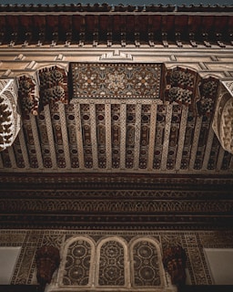 Elaborate and intricate ceiling design featuring detailed geometric patterns and floral motifs. The craftsmanship showcases ornate carvings and artistic elements typical of Moorish architecture. The woodwork is richly detailed with a variety of textures and depth.