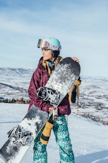 woman in black and white floral jacket and blue pants wearing black and white snow goggles
