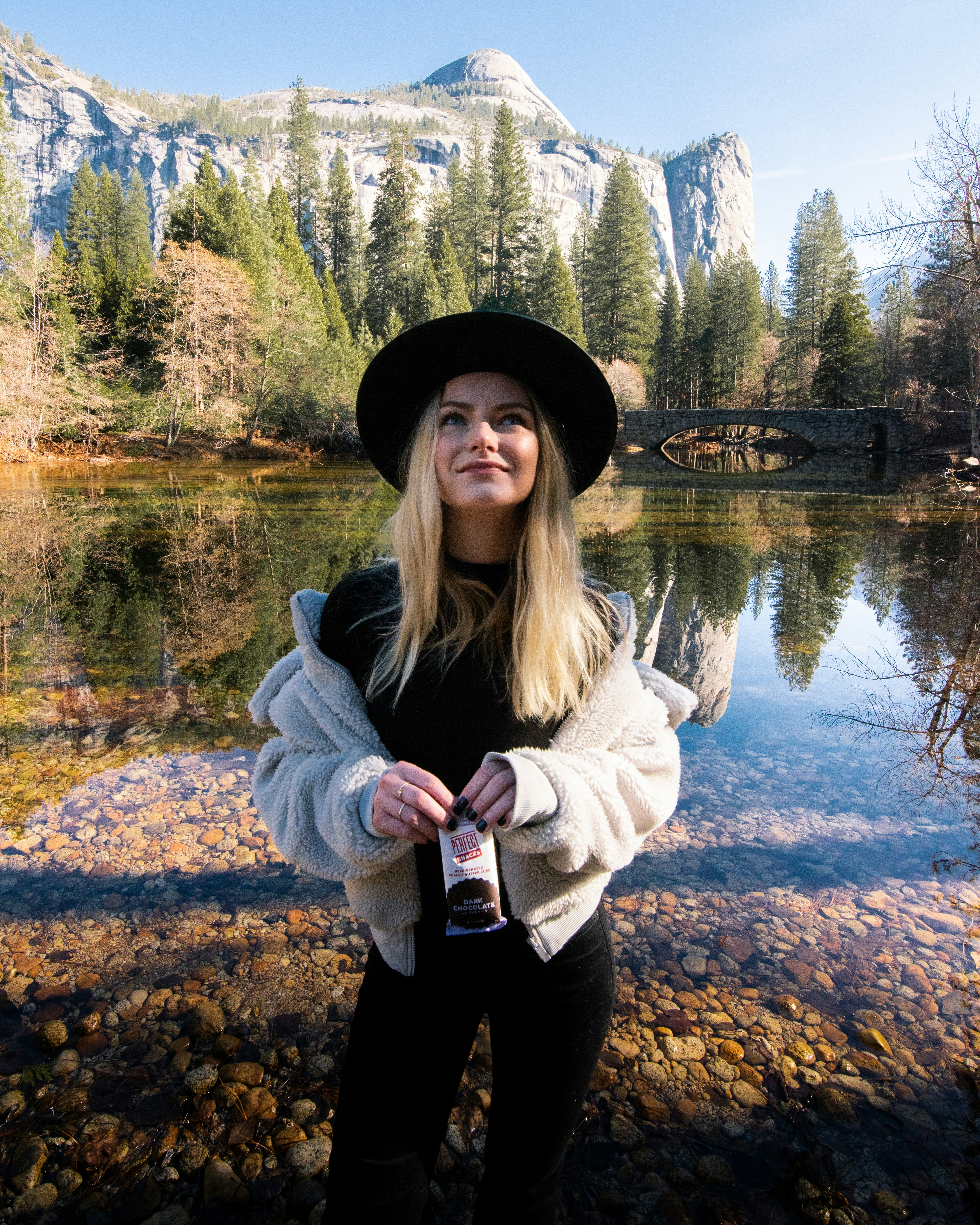 woman in gray jacket standing near lake during daytime