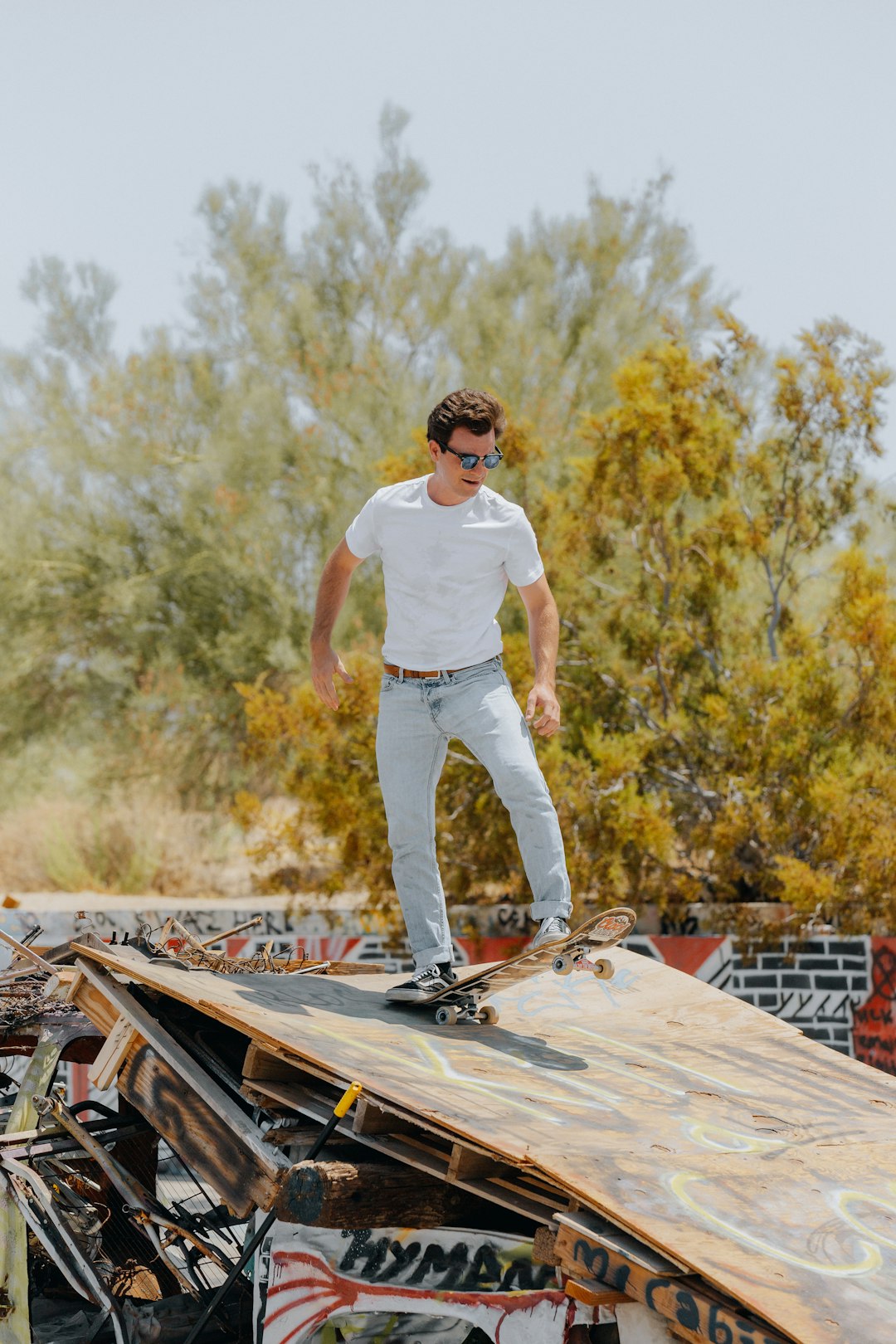 man in white t-shirt and white pants standing on brown wooden picnic table during daytime