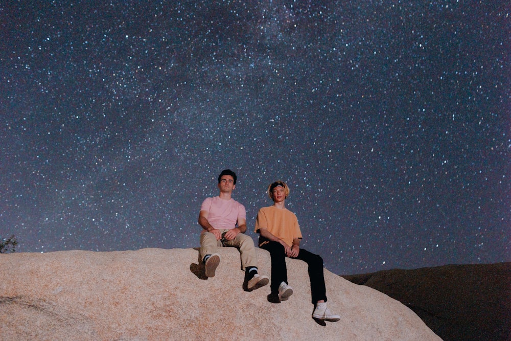 man and woman sitting on rock during night time