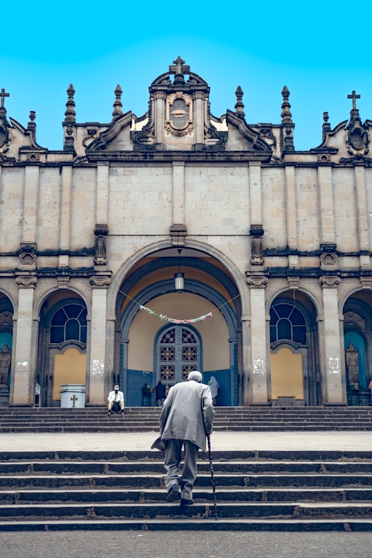 woman in white long sleeve dress walking on sidewalk near building during daytime in Holy Trinity Cathedral Ethiopia