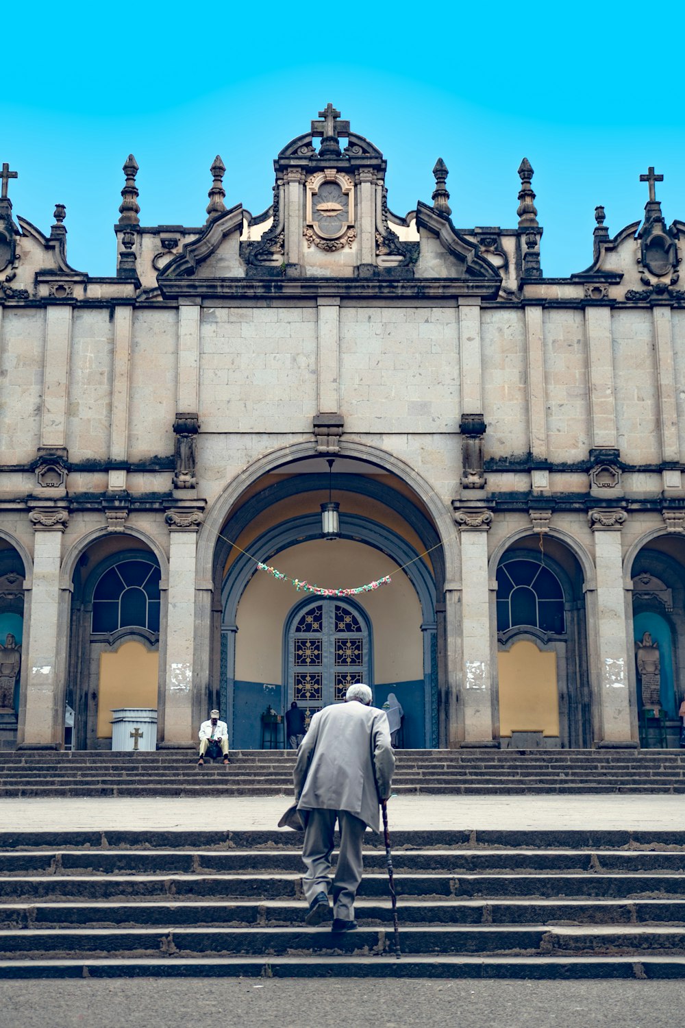 femme en robe blanche à manches longues marchant sur le trottoir près d’un bâtiment pendant la journée