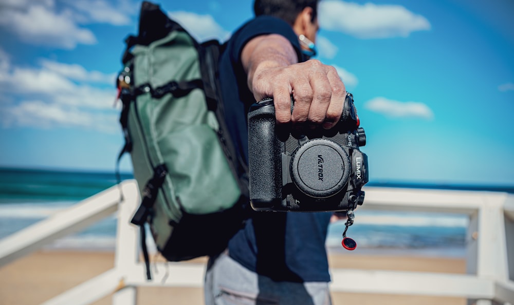 person in blue jacket and black pants holding black dslr camera