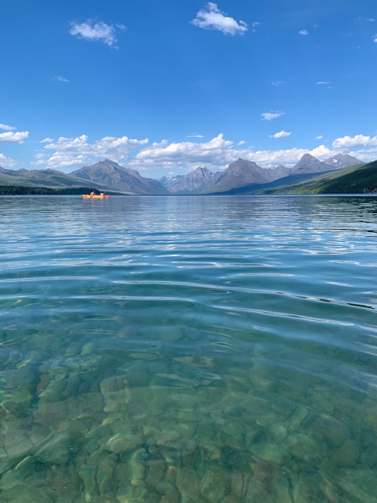 body of water near mountain under blue sky during daytime in Glacier National Park United States