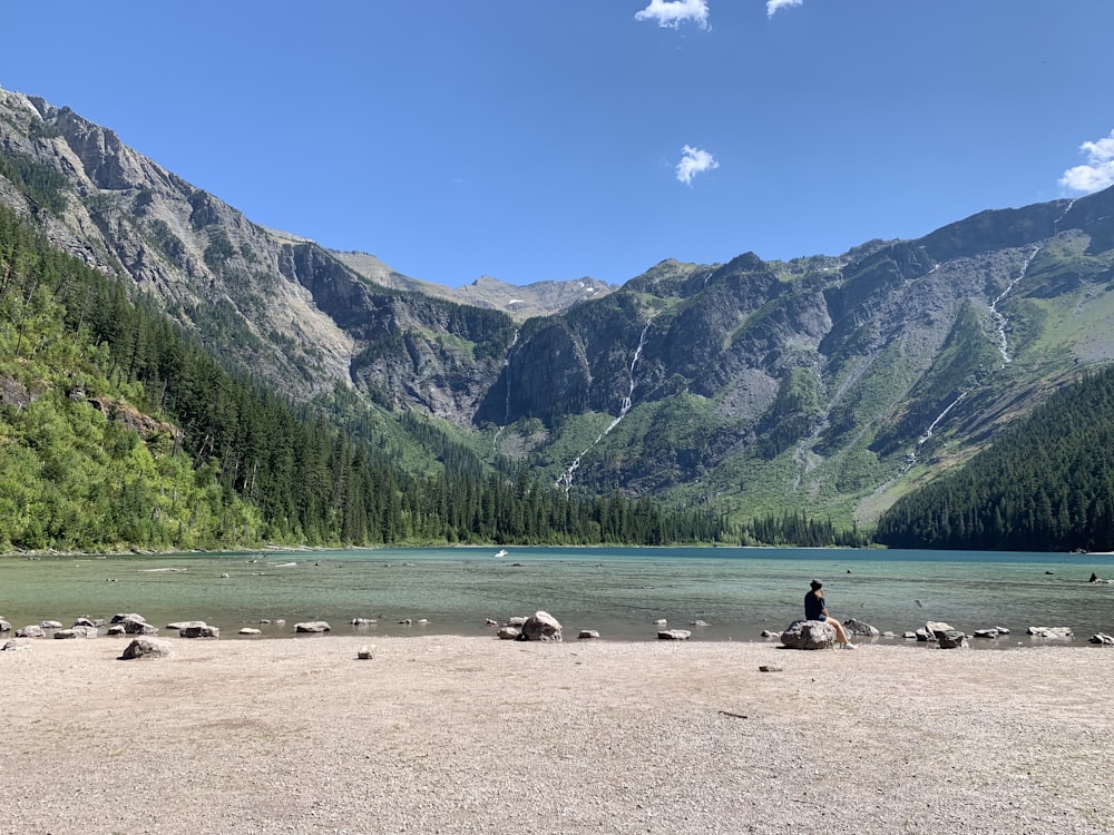 people on lake near green mountains during daytime