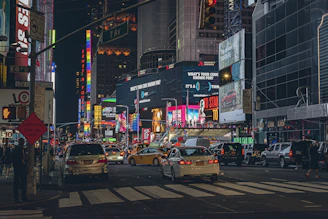 Nighttime city street glowing with neon signs and bustling crowds.