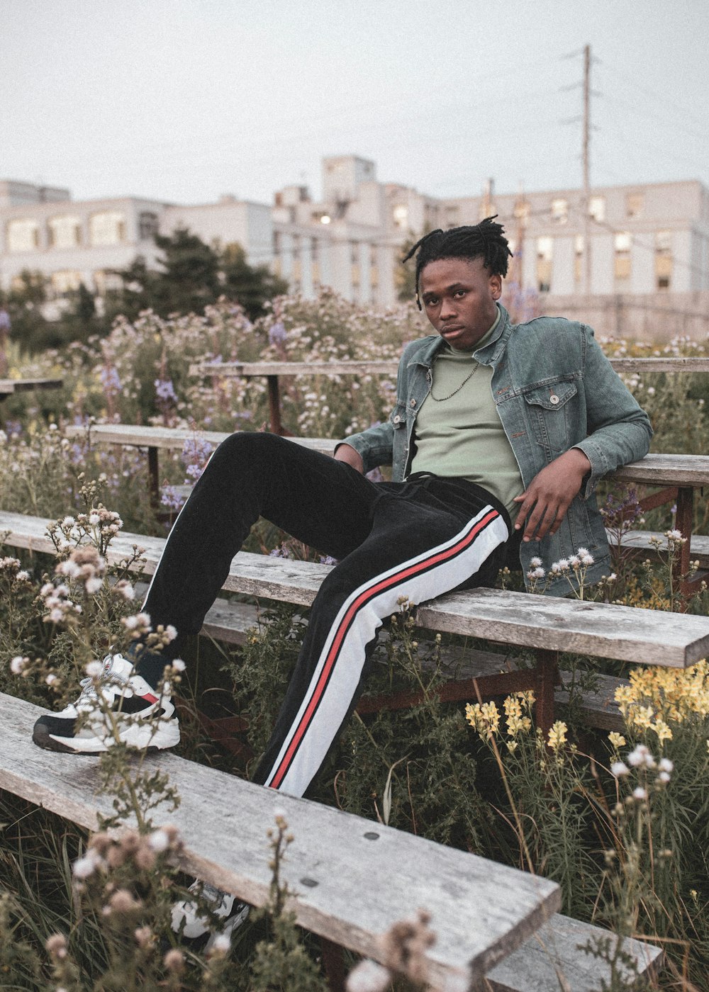 woman in green jacket and black pants sitting on brown wooden bench during daytime