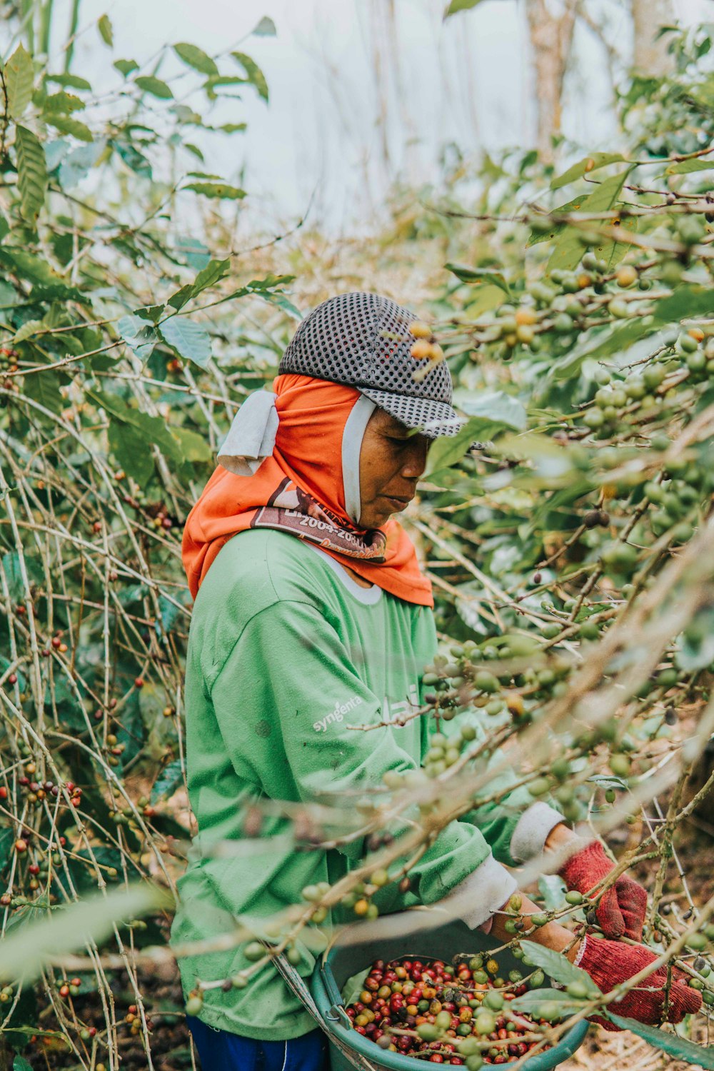 woman in green jacket standing near green plants during daytime