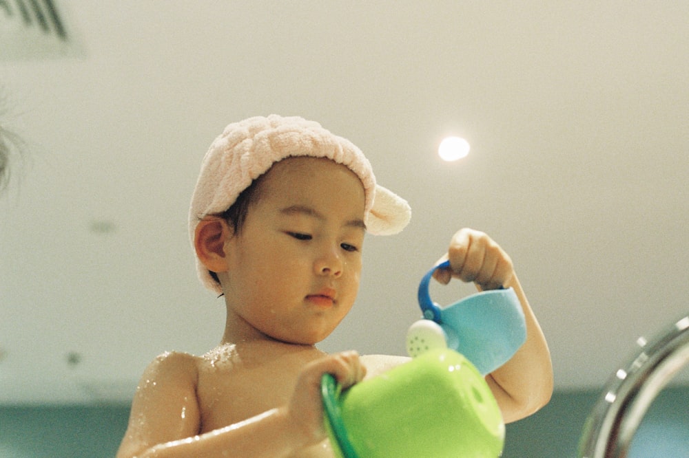 baby in white knit cap on green plastic container