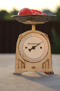 A sleek equilibra kitchen scale on a wooden countertop next to fresh ingredients.