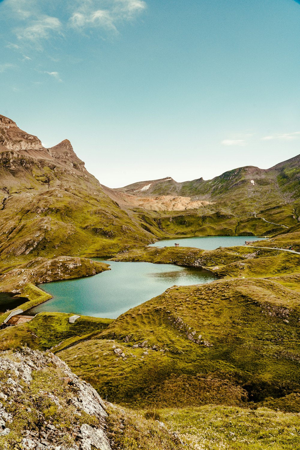 green and brown mountains beside lake under blue sky during daytime