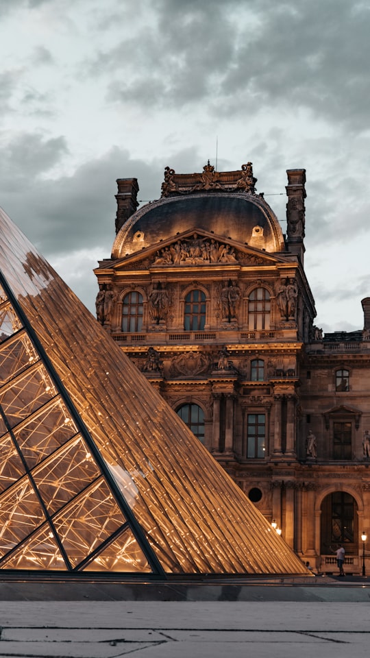 brown concrete building under white clouds during daytime in Louvre France