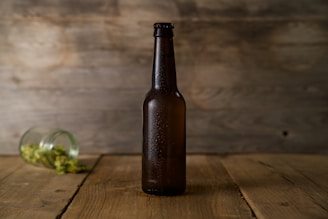 A close-up of a chilled craft beer bottle with condensation, set against a rustic wooden table.