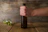 A happy customer holding a cold craft beer bottle with a rustic wooden background.