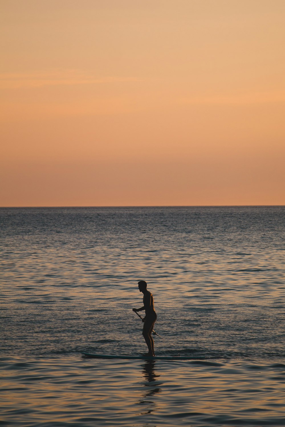 Silhouette einer Frau, die während des Sonnenuntergangs am Strand spazieren geht