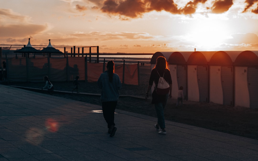 man and woman walking on sidewalk during sunset