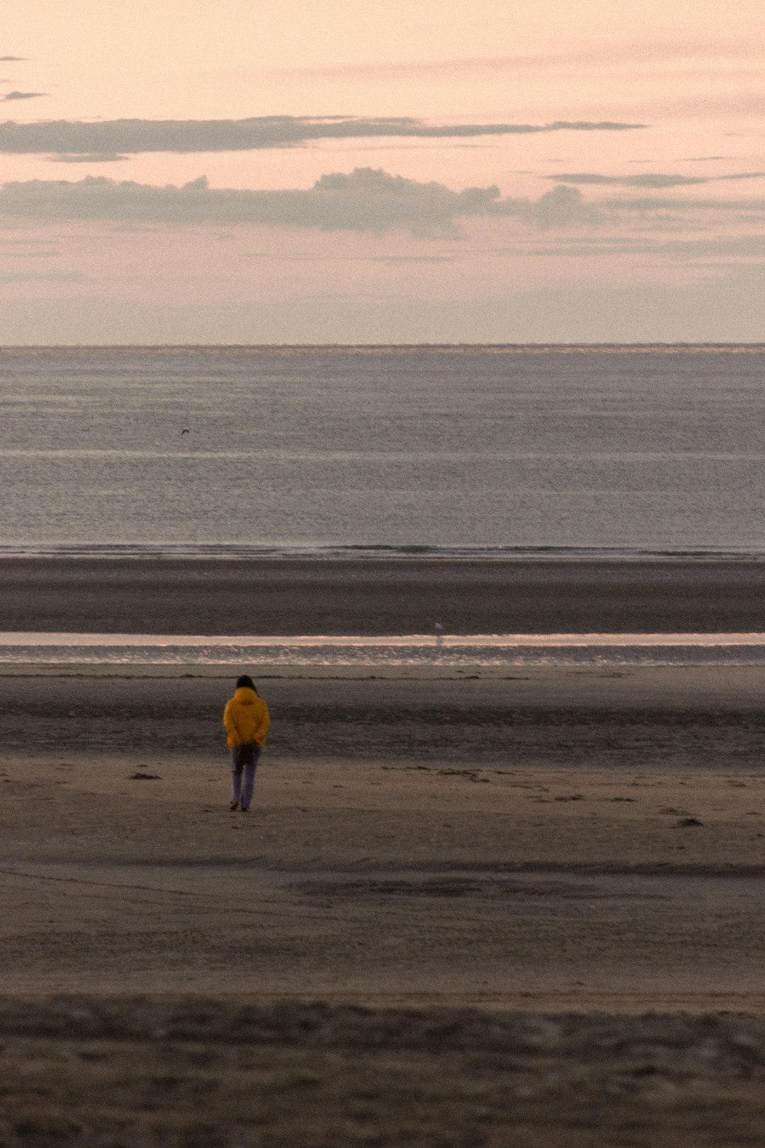 person in black jacket walking on beach during daytime