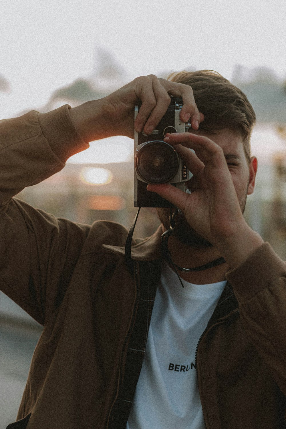 woman in brown jacket holding black camera