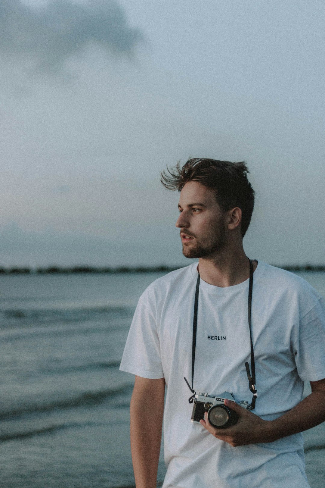 man in white crew neck t-shirt standing near body of water during daytime