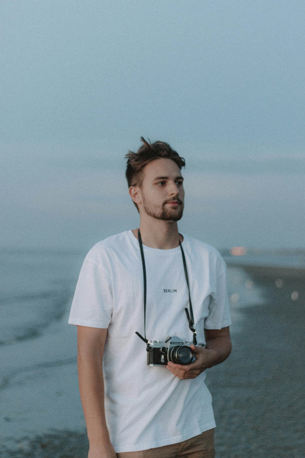 Mann im weißen Rundhals-T-Shirt mit schwarzer DSLR-Kamera