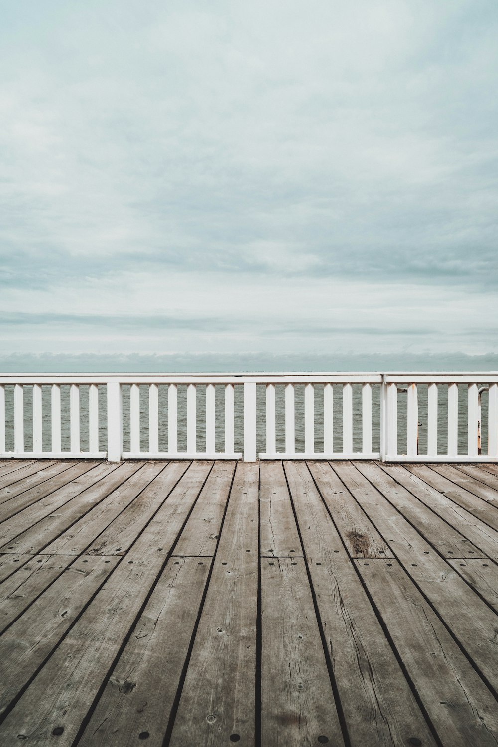 muelle de madera blanca bajo el cielo nublado blanco durante el día