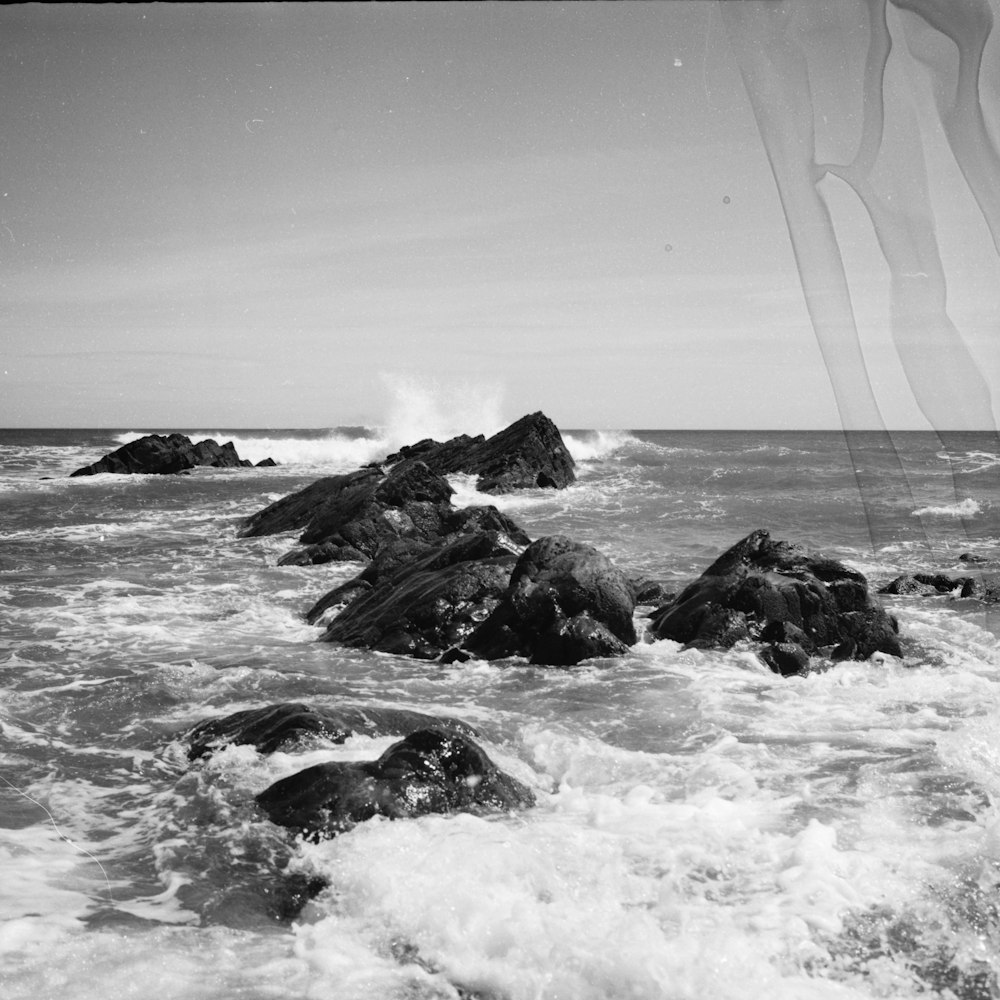 Foto en escala de grises de la formación rocosa en el mar