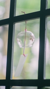 A smooth wooden chime hanging gracefully amidst green foliage, capturing sunlight