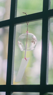 A delicate sun catcher gleaming with vibrant beads hanging by a window.