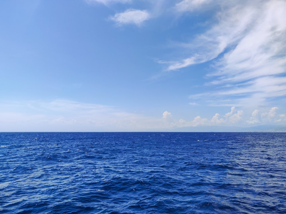blue ocean under blue sky and white clouds during daytime