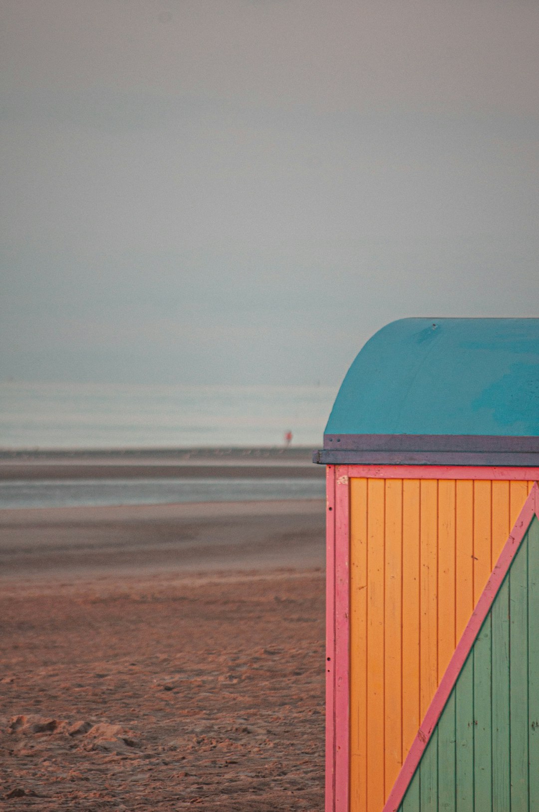 red and blue wooden shed on brown sand during daytime