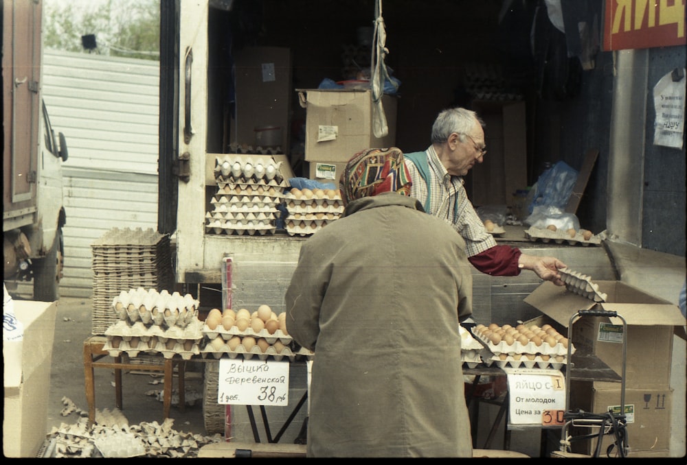 uomo in camicia a maniche lunghe marrone in piedi davanti alla bancarella di frutta