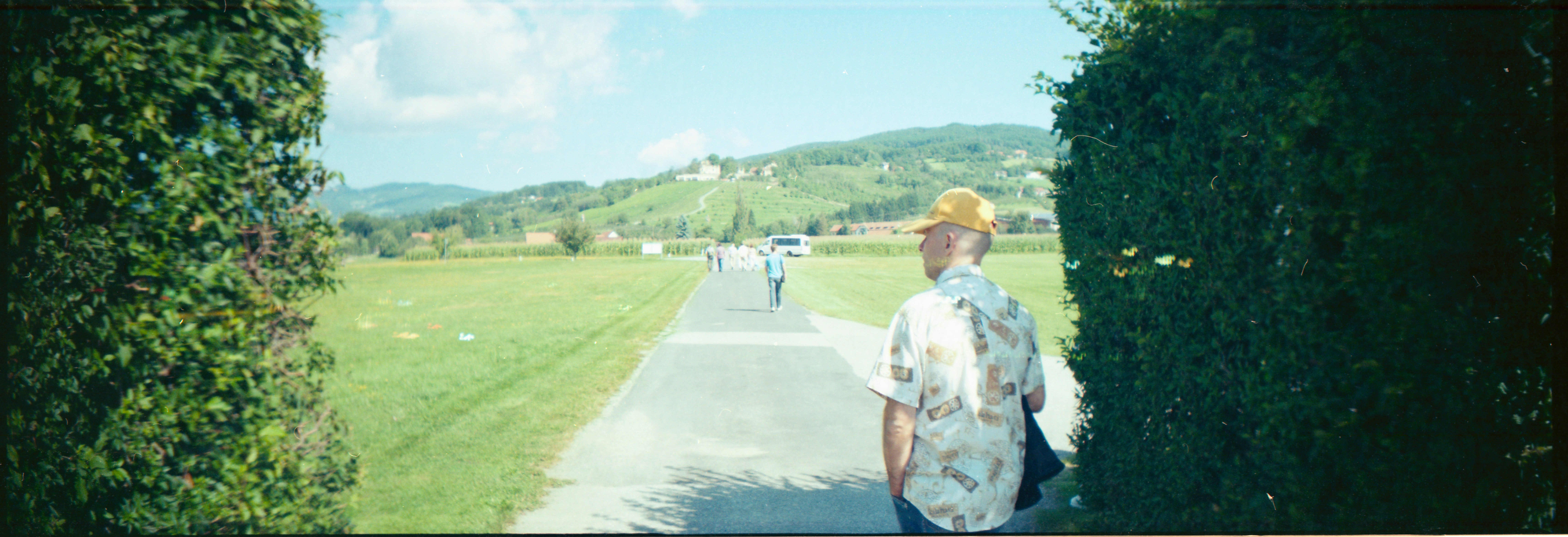 man in white t-shirt and blue denim shorts standing on road during daytime