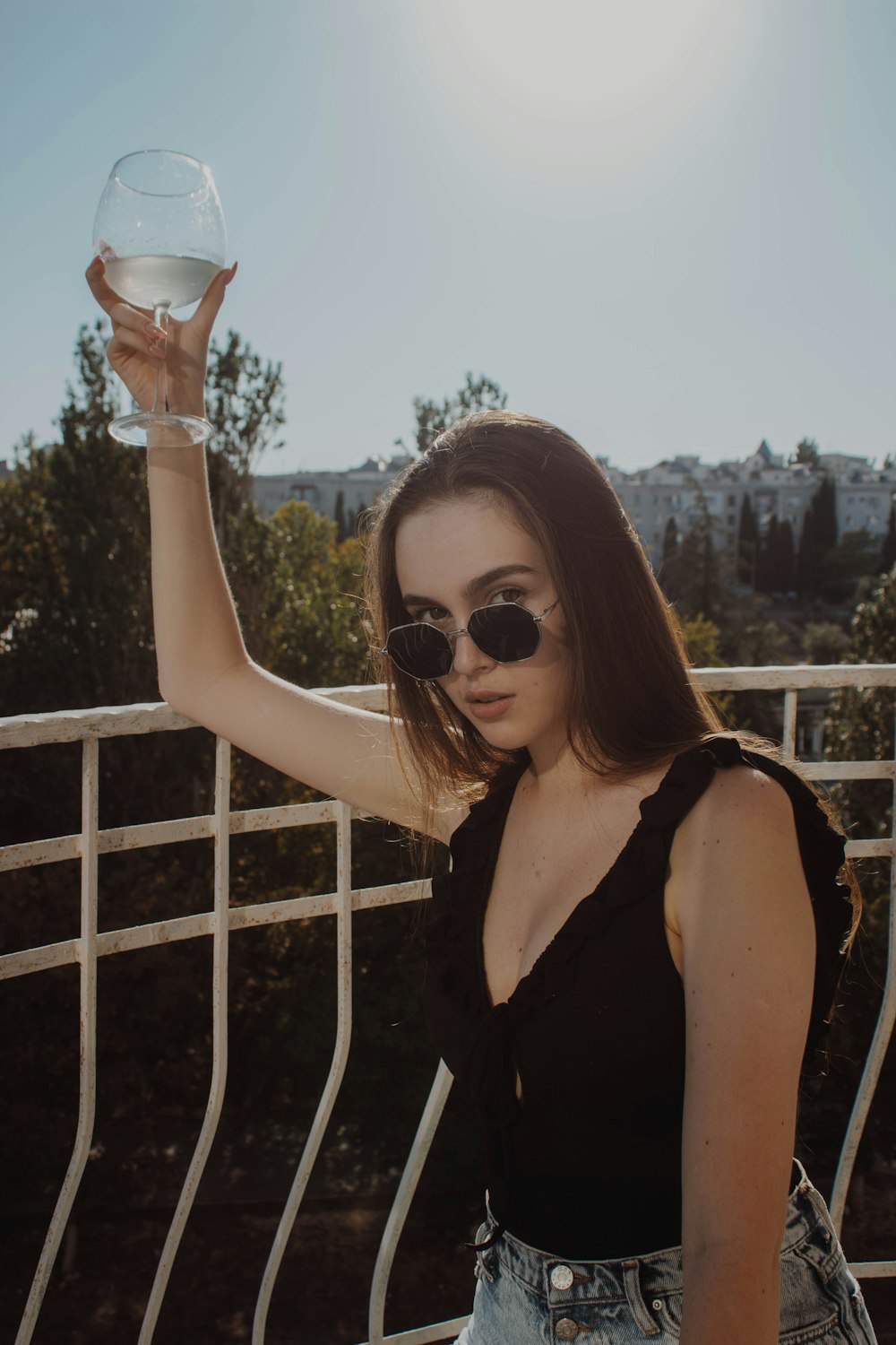 woman in black tank top holding clear drinking glass