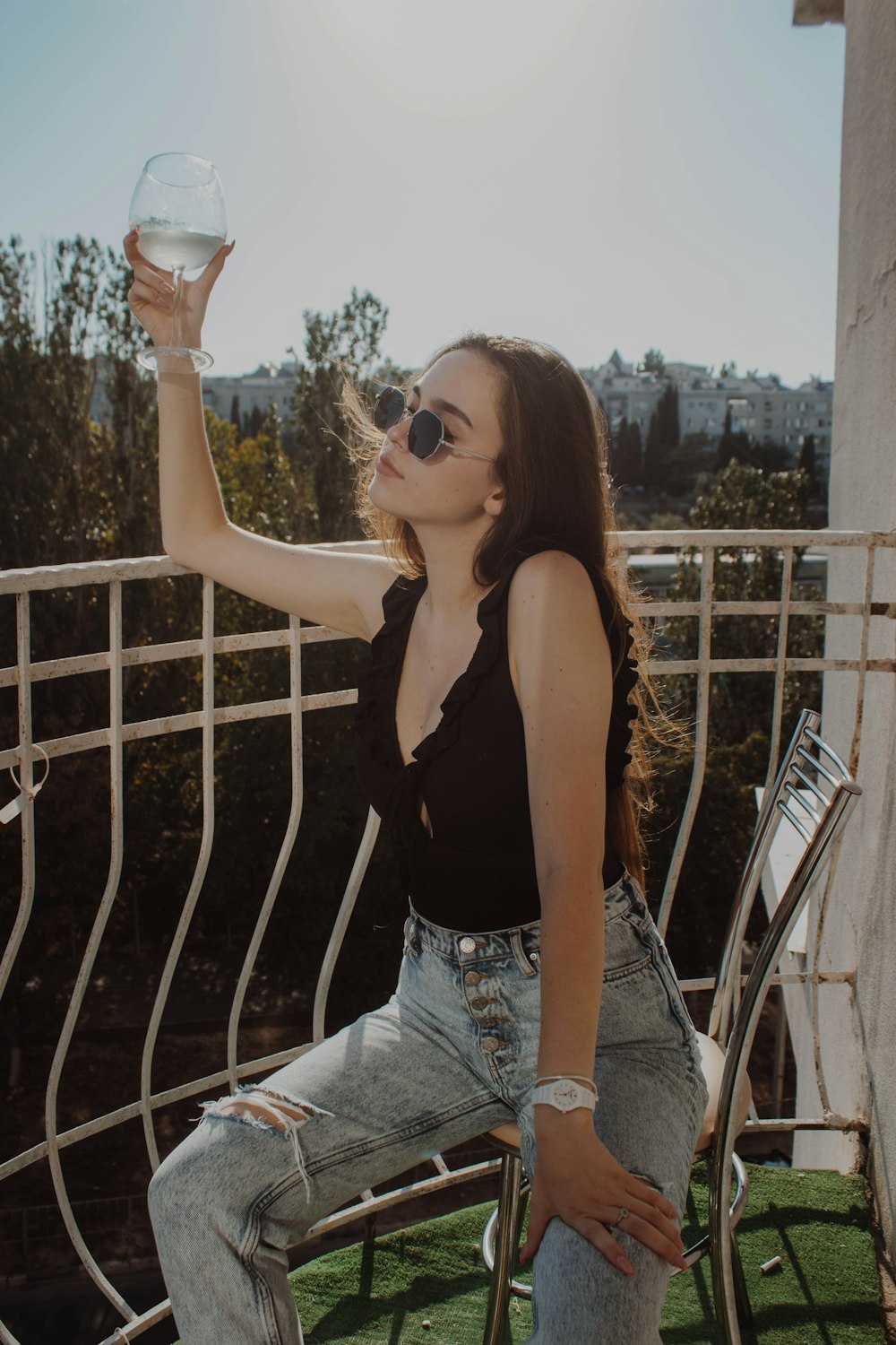 woman in black tank top and blue denim shorts holding clear drinking glass