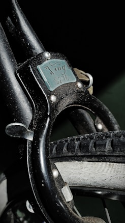 A close-up view of a bike lock attached to a bicycle wheel. The lock is labeled 'Ving 5276' and appears worn, with scratches visible on the surface. The bicycle tire is also detailed, showing the treads and slight wear.