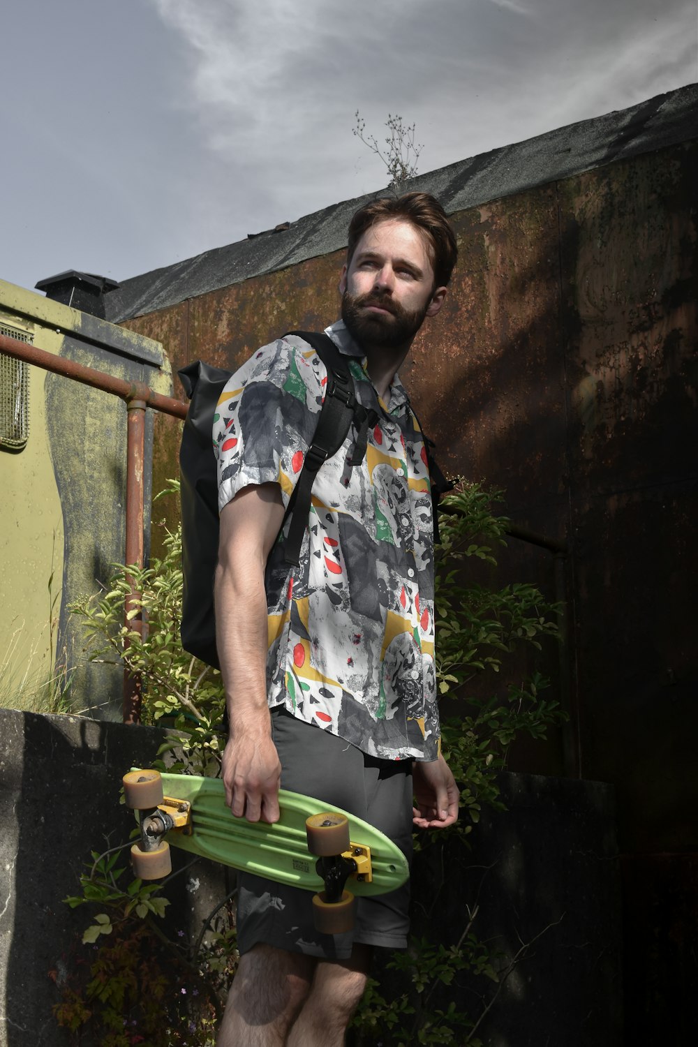 homem em branco azul e amarelo botão floral até t-shirt em pé perto da parede de concreto marrom