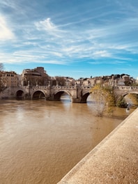 brown concrete bridge over river under blue sky during daytime