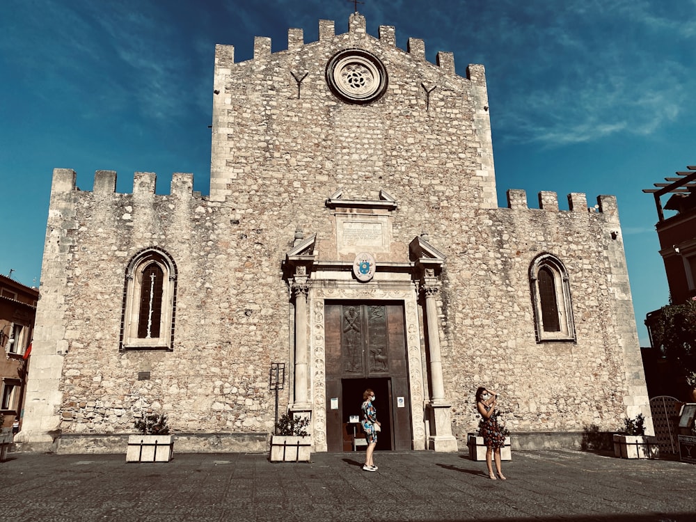 persone che camminano vicino a un edificio in cemento marrone sotto il cielo blu durante il giorno