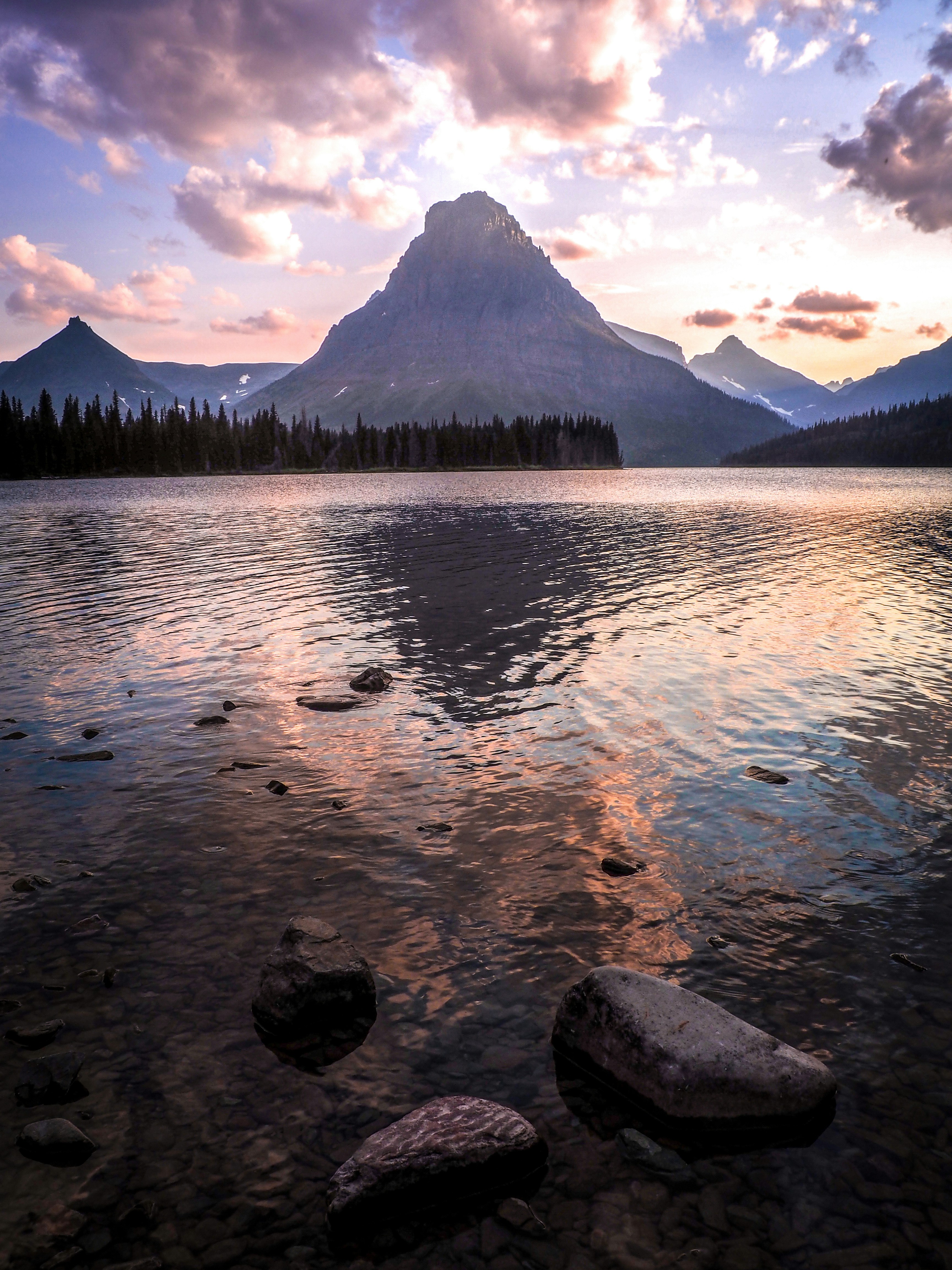 body of water near green trees and mountain during daytime