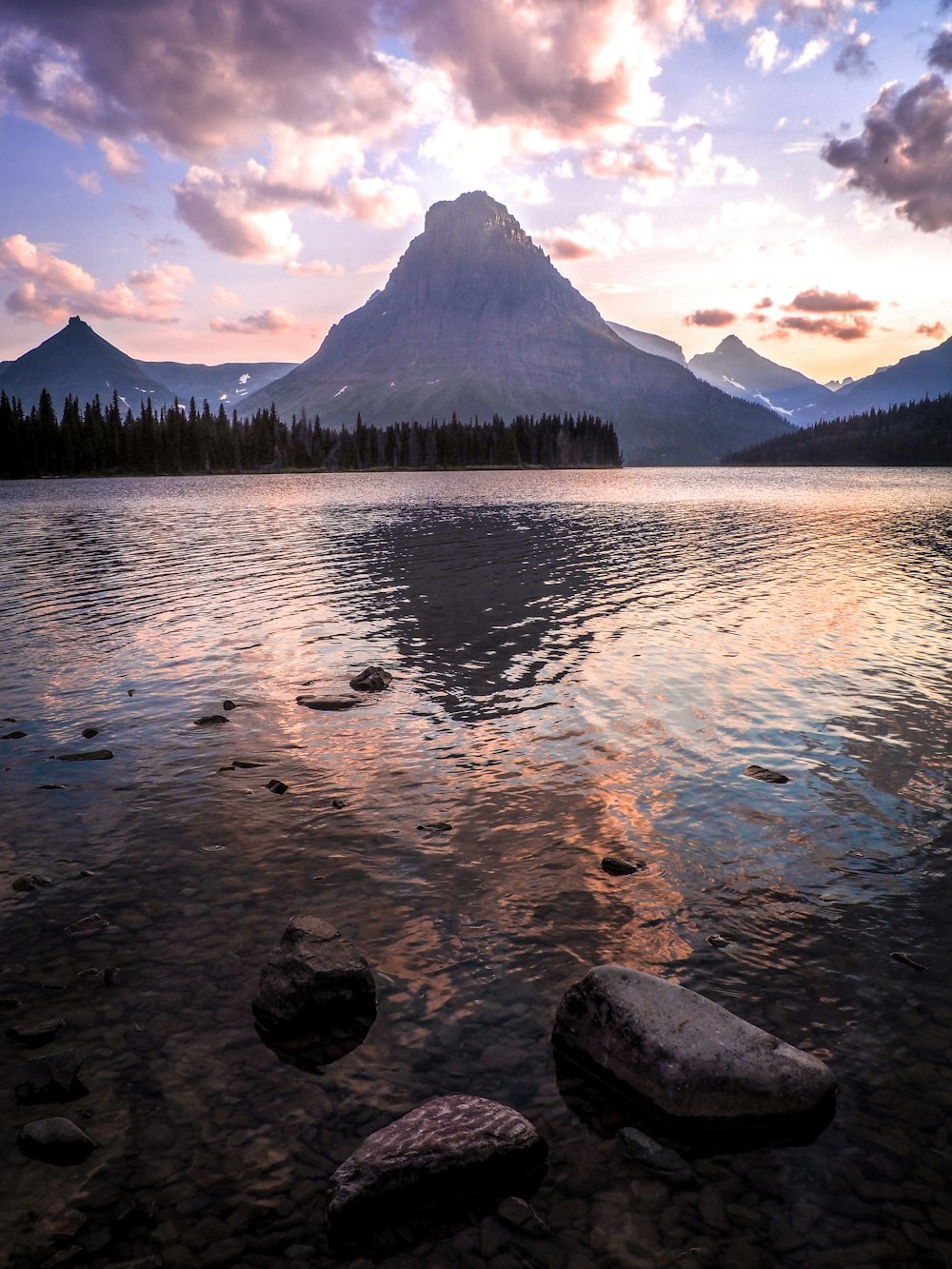 body of water near green trees and mountain during daytime