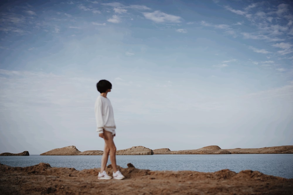 man in white t-shirt standing on brown sand during daytime