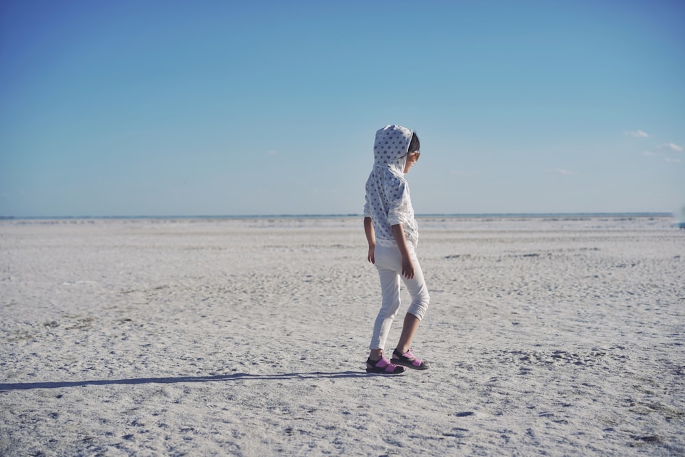 woman in white dress walking on beach during daytime