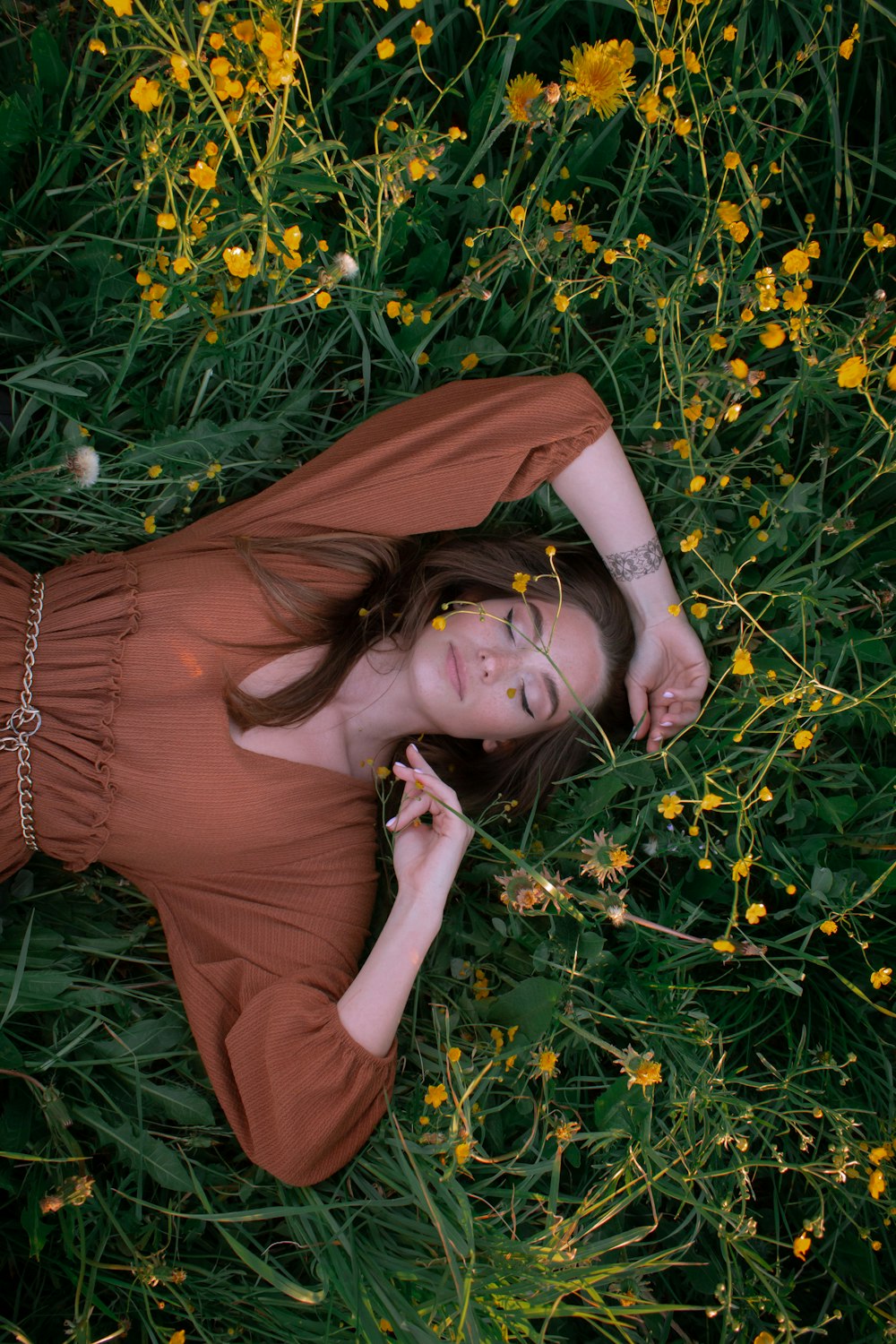 Frau im braunen Langarmhemd liegt auf grünem Rasen