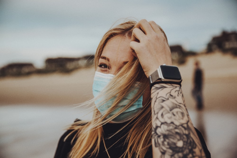 woman in black and white floral long sleeve shirt covering her face with her hand