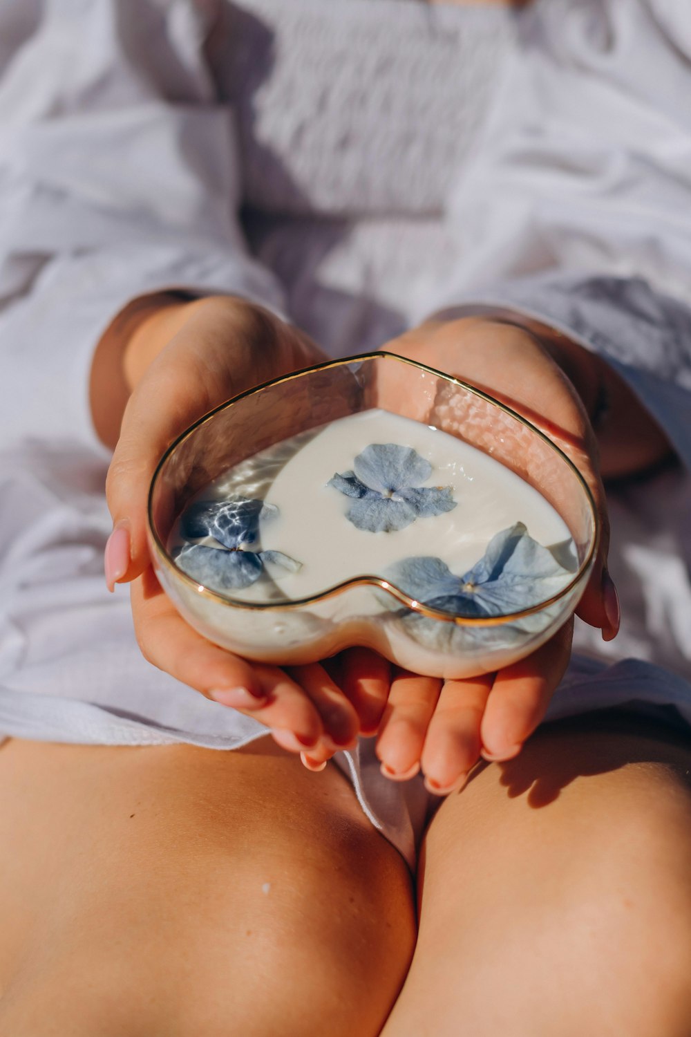 a woman is holding a bowl with blue flowers in it