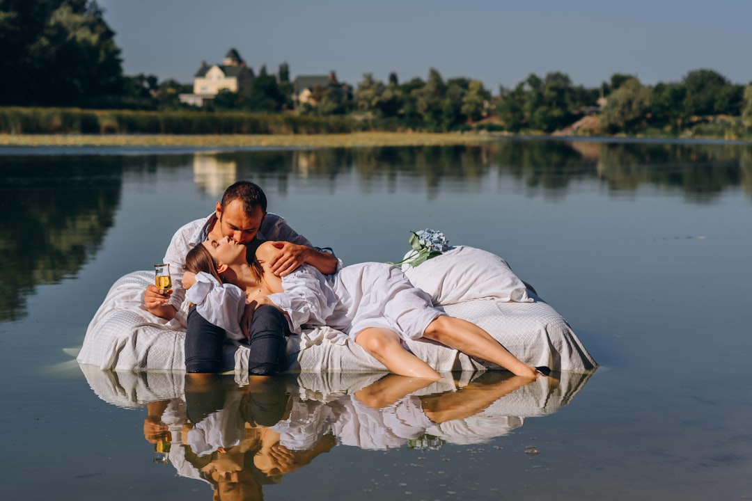 couple kissing on lake during daytime