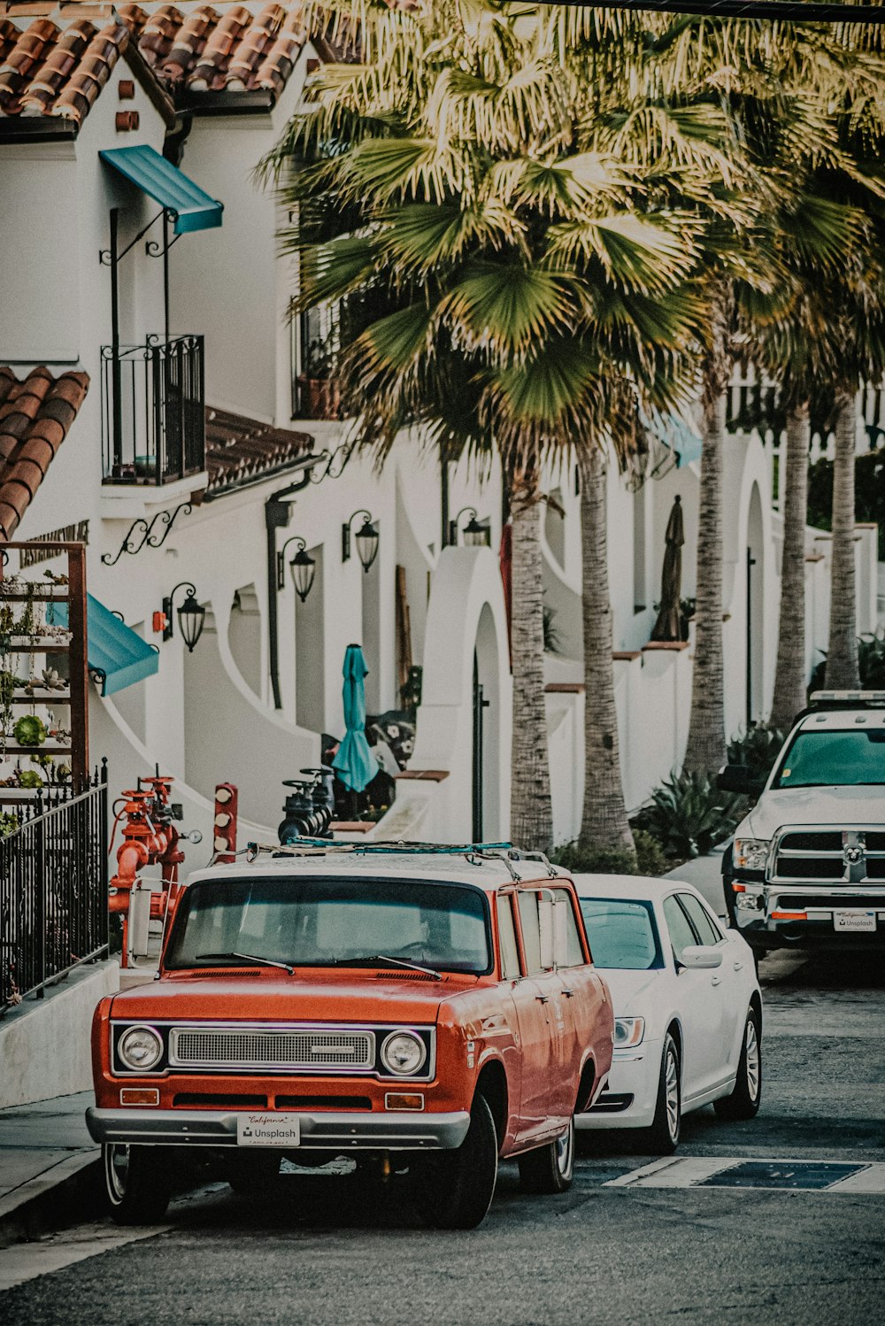 red and white vintage car parked beside white concrete building during daytime